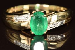 A 9ct gold ring set with an oval cut emerald of approximately 0.7ct and diamonds, 2g, size P