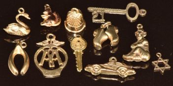 Eleven 9ct gold charms including thimble, squirrel, key, pixie, wishbone, AA badge, swan, clogs,