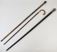 Three walking sticks including two with white metal mounts, one with carved ebony decoration and a