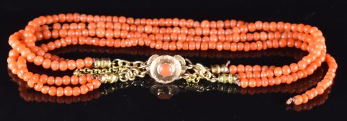 A four strand coral bracelet with yellow metal clasp set with a coral cabochon, 16.5cm (one strand