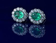 A pair of 18ct white gold earrings each set with an oval cut emerald of approximately 2ct surrounded