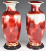 Pair of Chinese Sang de Boeuf pedestal vases with red seal marks to bases and wooden stands,