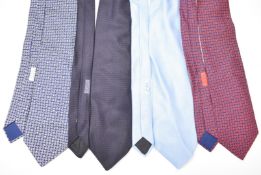Four Hermès silk ties including plain navy blue, pale blue, and two with letter 'e' decoration