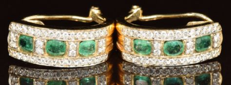 A pair of 14k gold earrings each set with three oval cut emeralds of approximately 0.15ct each and