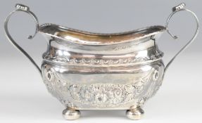 Victorian hallmarked silver sugar bowl with embossed decoration, raised on four ball feet,