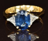 An 18ct gold ring set with an oval cut sapphire of approximately 2.2ct and two trillion cut diamonds