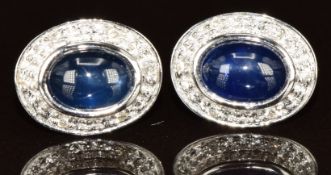 A pair of 18ct white gold earrings each set with a sapphire cabochon and diamonds, 2.3g