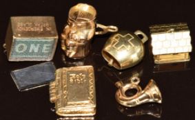 Three 9ct gold charms in the form of a French horn, Holy Bible and one shilling note, 9.2g, together