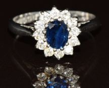An 18ct white gold ring set with an oval cut sapphire of approximately 0.5ct surrounded by twelve