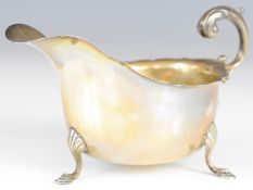 George VI hallmarked silver sauce boat with scroll handle, raised on three feet, Chester 1933, maker