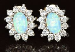 A pair of 9ct gold earrings each set with a synthetic opal cabochon surrounded by cubic zirconia,