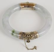 A jadeite bangle with silver hinge and clasp, 83mm in diameter.