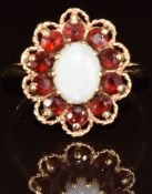 A 9ct gold ring set with an opal cabochon surrounded by garnets, 3.9g, size P