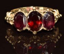 A 9ct gold ring set with three oval garnets, 3.9g, size M