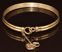 A 9ct gold bangle with heart padlock and safety chain, 10.5g, 6 x 4.9cm