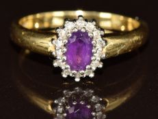 An 18ct gold ring set with an oval cut amethyst surrounded by diamonds, 4.4g, size O