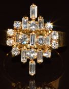 An 18ct gold ring set with twelve round cut diamonds and nine baguette cut diamonds, 6.2g, size M