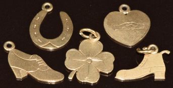 Five yellow metal charms / pendant in the form of a horseshoe, four leaf clover, two shoes and a