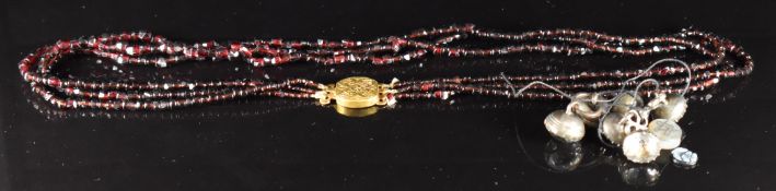 Early Victorian three strand garnet necklace, the yellow metal clasp with scrolling decoration, a