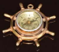 A 9ct gold charm in the form of a ship's wheel set with a compass, 4.7g, 2.8cm