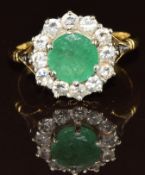 An 18ct gold ring set with a round cut emerald of approximately 1.5ct surrounded by twelve diamonds,