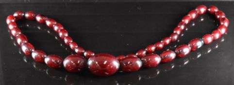 A cherry amber necklace made up of 44 graduated oval beads, the largest 33x24mm and the smallest