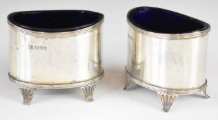 Pair of Edward VII hallmarked silver open salts with blue glass liners and each raised on four feet,