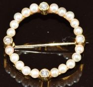 An 18ct gold circular brooch set with pearls and four round cut diamonds, the total diamond weight