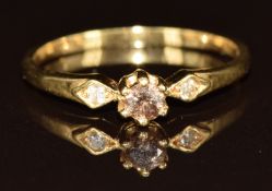 An 18ct gold ring set with a round cut brown diamond and two further diamonds to the shoulders, 2.