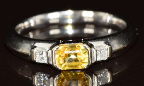 An 18ct white gold ring set with a mixed cut yellow sapphire of approximately 0.4ct and two princess