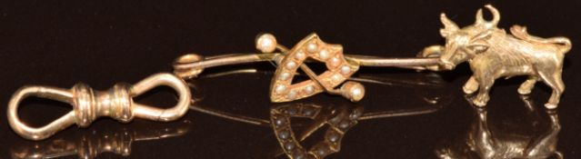 A 9ct gold charm in the form of a bull / cow (2.8g), 9ct gold double dog clip (1.7g) and 15ct gold