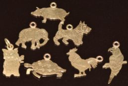 Seven yellow metal charms / pendants in the form of a pig, Scottie dog, cat, parrot, elephant,