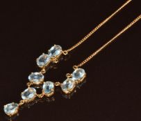 An 18ct gold necklace set with seven oval cut topaz, each approximately 0.7ct, and a pear cut