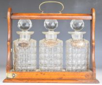 Oak and silver plated three bottle tantalus with cut glass bottles and hallmarked silver bottle