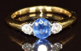 An 18ct gold ring set with an oval cut sapphire of approximately 0.5ct and two diamonds, each