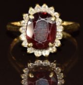 An 18ct gold ring set with an oval cut garnet surrounded by diamonds, 4.2g, size Q