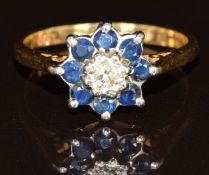 An 18ct gold ring set with a diamond surrounded by sapphires, 4.1g, size O