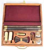 A 12 bore shotgun cleaning kit with rosewood and brass rods, chrome oil bottles etc, in hardwood