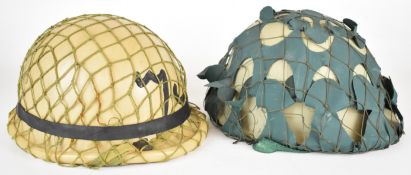 Two Iraqi helmets comprising M90 helmet with netting, Arabic text to front, rubber rim, liner and