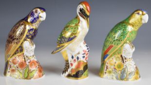 Three Royal Crown Derby bird paperweights comprising bronze winged parrot, green woodpecker and