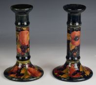 A pair of William Moorcroft candlesticks decorated in the Pomegranate pattern with open pomegranates