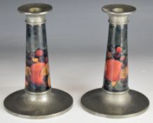 A pair of William Moorcroft candlesticks decorated in the Pomegranate pattern, with Tudric pewter