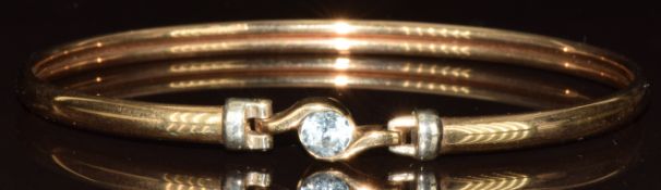 A 9ct gold bangle set with a round cut topaz, 5.4g