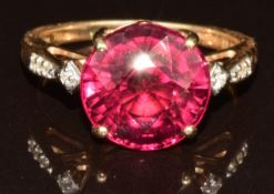 A 14k gold ring set with a round cut Malawi garnet of approximately 7.7ct and diamonds, with