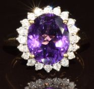 A 9ct gold ring set with an oval cut amethyst surrounded by diamonds, the total diamond weight