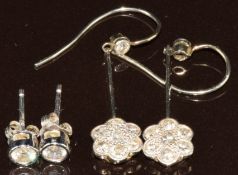A pair of white gold earrings each set with a diamond and seven diamonds in a cluster together