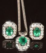 An 18ct white gold pendant set with an oval cut emerald of approximately 0.5ct surrounded by round