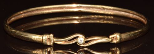 A 9ct gold bangle set with a round brilliant cut diamond, 5.2g