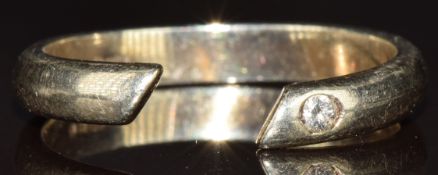 A 9ct white gold torque ring set with a diamond, 2.7g, size K