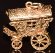 A 9ct gold charm in the form of a caravan, opening to reveal a lady carrying a basket, 8.2g